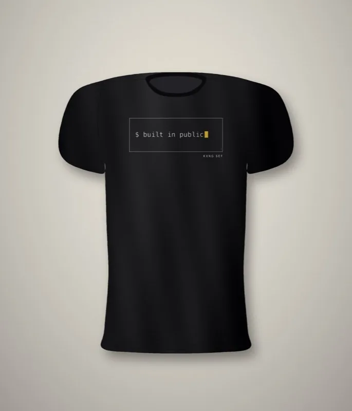 Black unisex tee with a terminal-style front print reading built in public, with a gold cursor block